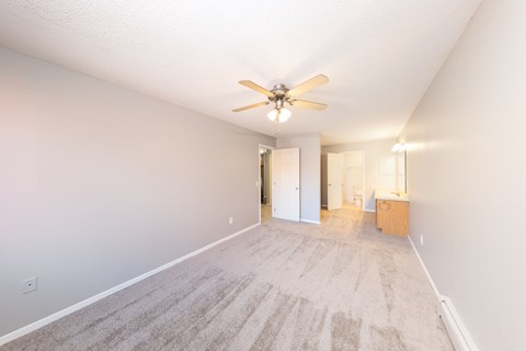 a spacious living room with carpet and a ceiling fan
