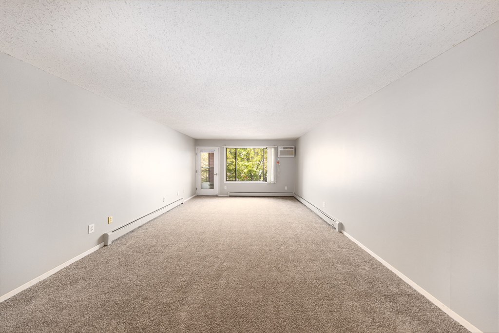 a spacious living room with white walls and carpet