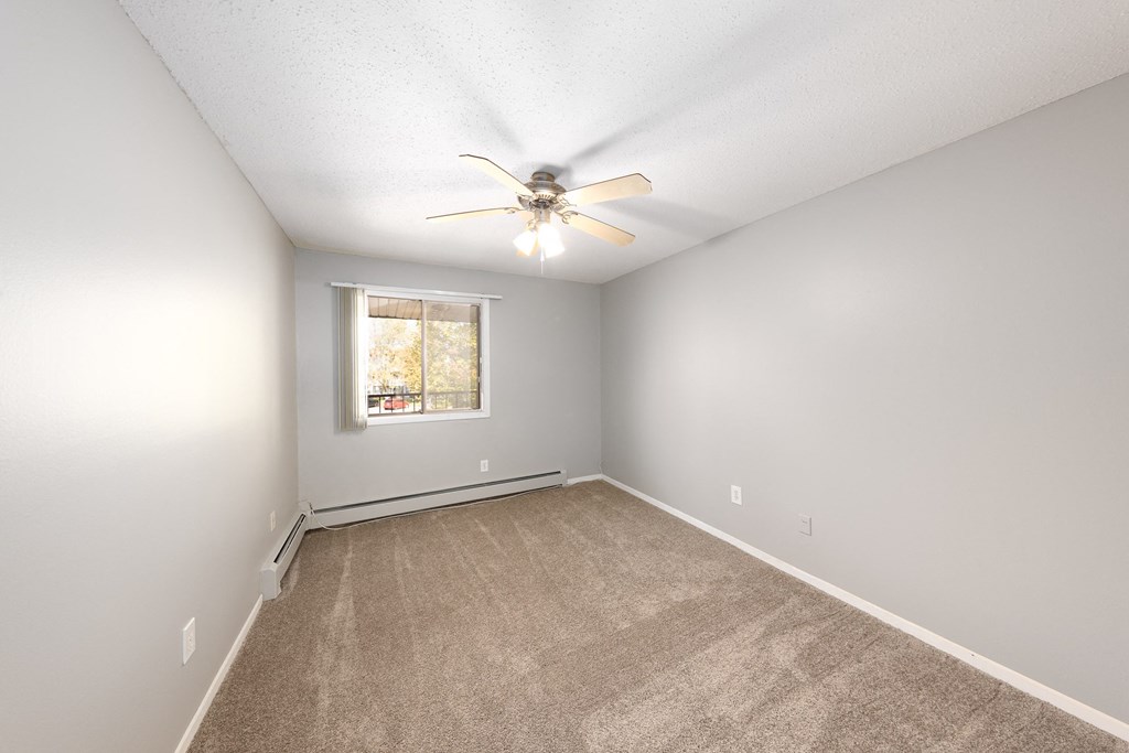an empty room with carpet and a ceiling fan
