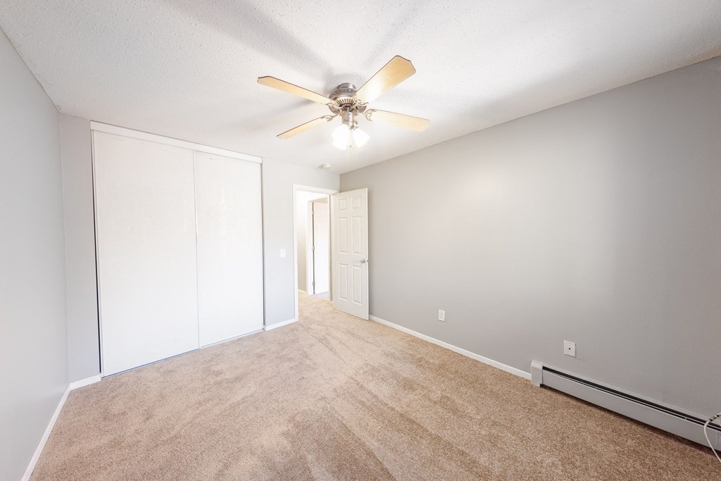 a spacious living room with carpet and a ceiling fan