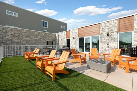 a patio with orange chairs and a fire pit