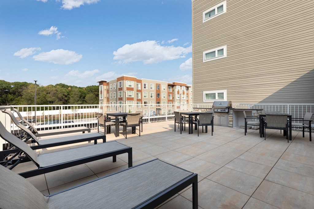 a patio with tables and chairs and a grill on a balcony