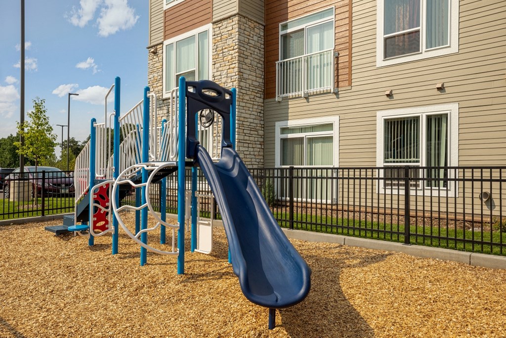 a playground with a blue slide at an apartment complex
