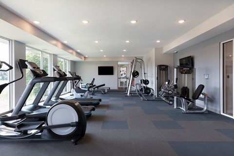 a gym with treadmills and other exercise equipment in a building with large windows