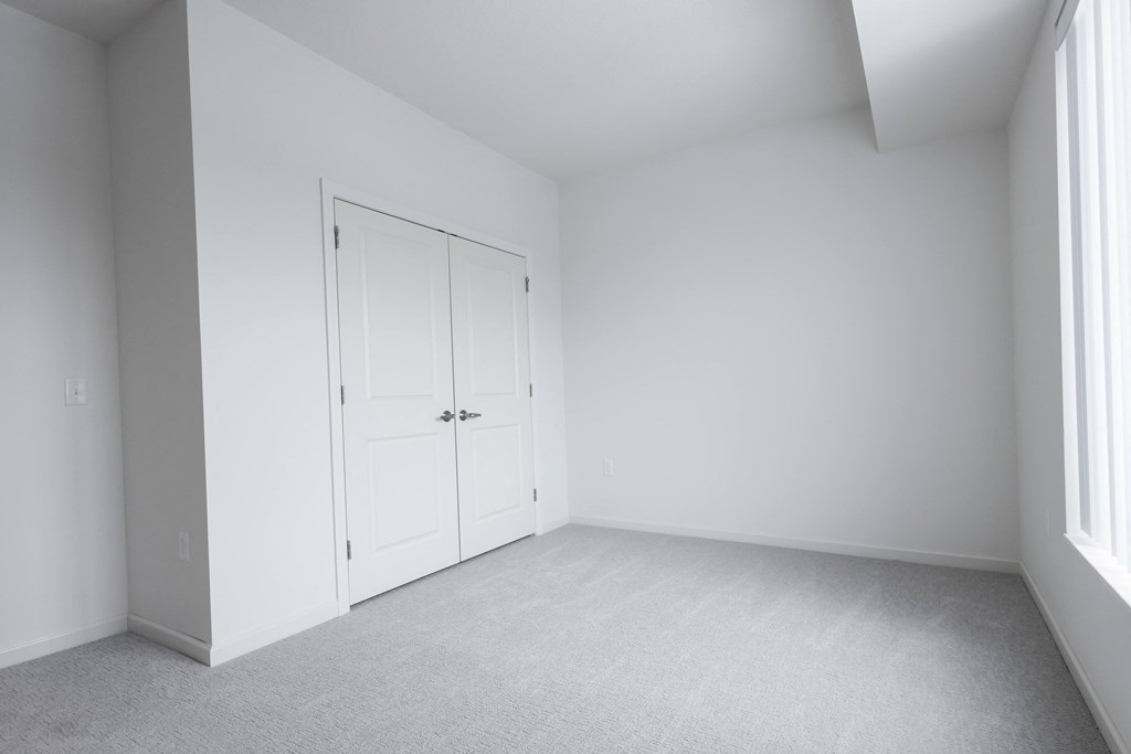 an empty room with white walls and a door to a closet