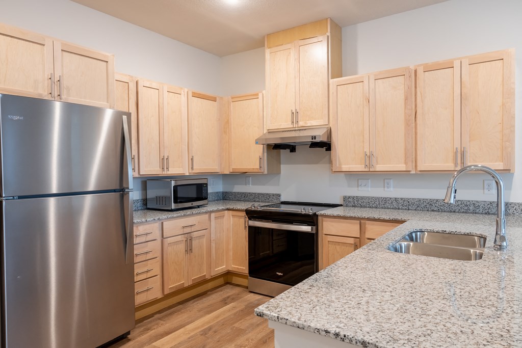 a kitchen with granite counter tops and wooden cabinets