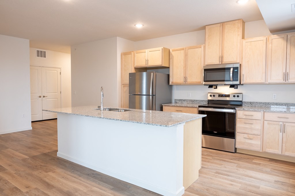 a kitchen with a large island and a stainless steel refrigerator