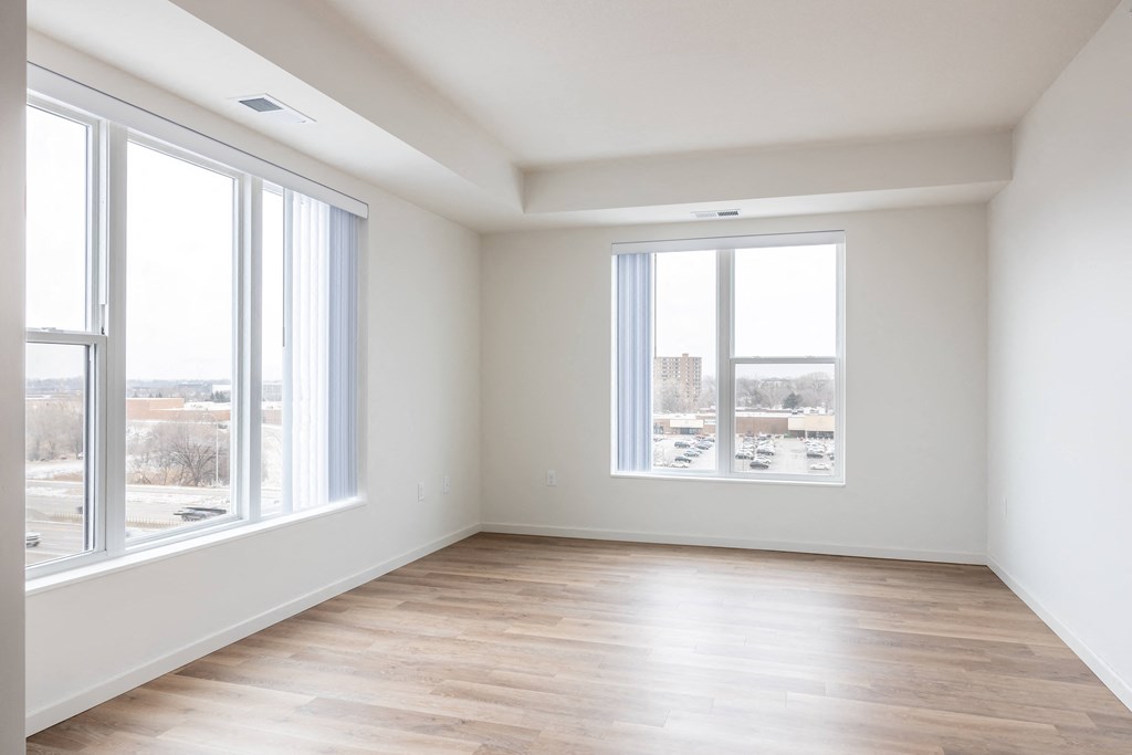 an empty living room with large windows and a wooden floor