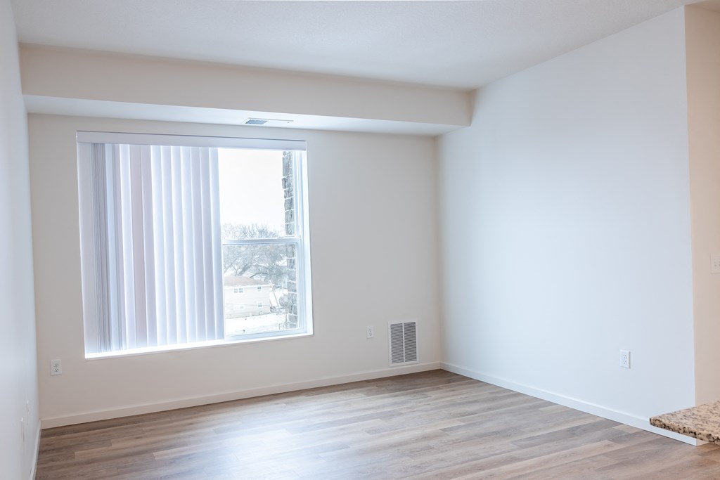 an empty living room with a large window and wooden floors
