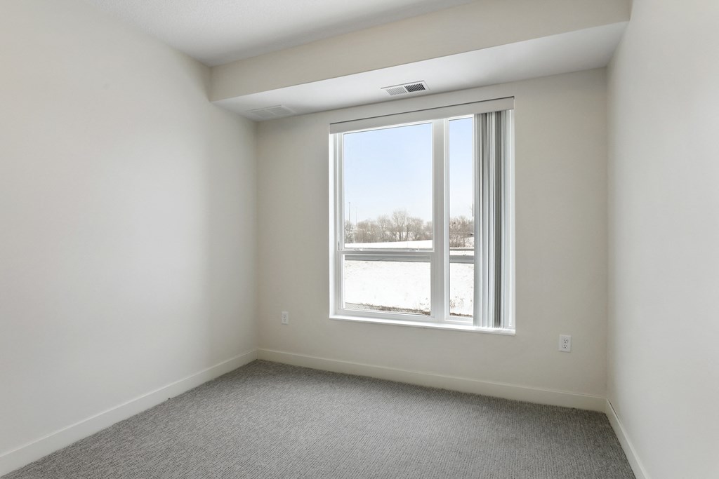 an empty room with a large window and carpeting