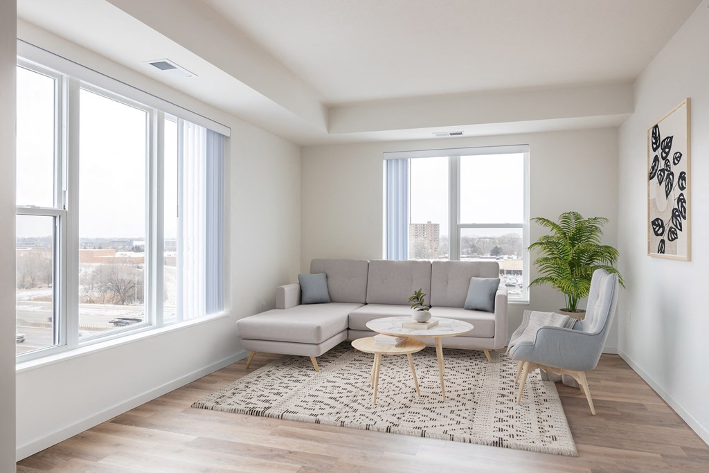 a living room with a gray couch and a rug and large windows
