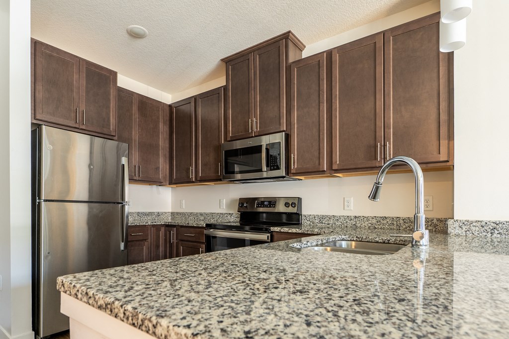 a kitchen with granite countertops and dark wood cabinets at Sonder House, Brooklyn Center
