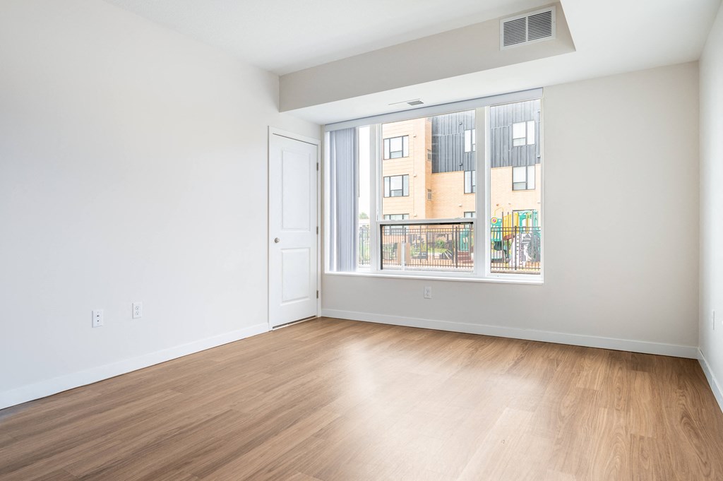 a bedroom with a large window and hardwood floors at Sonder Point 50+ Apartments, Minnesota, 55430