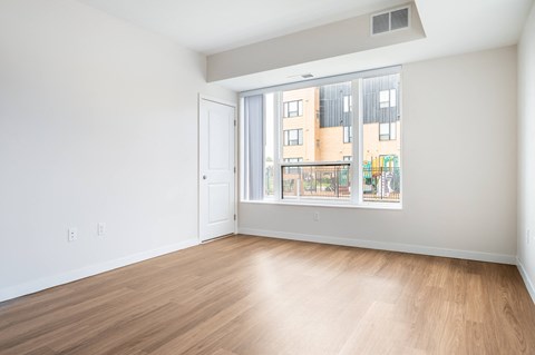 a bedroom with a large window and hardwood floors at Sonder Point 50+ Apartments, Minnesota, 55430