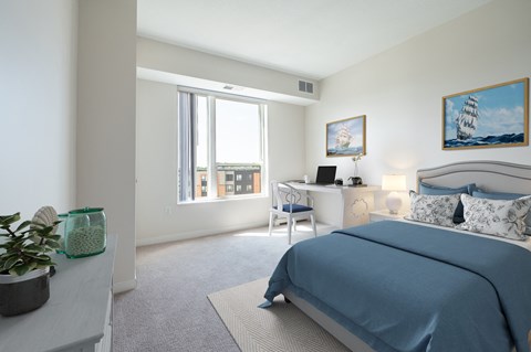 a bedroom with a bed and a desk with a computer at Sonder Point 50+ Apartments, Brooklyn Center, MN, 55430