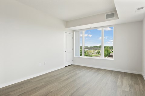 A room with a white door and a window showing a view of a residential area at Sonder Point 50+ Apartments, Brooklyn Center