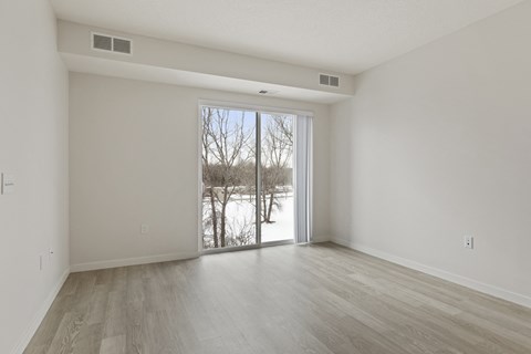 A spacious room with a sliding glass door leading to a snowy landscape.