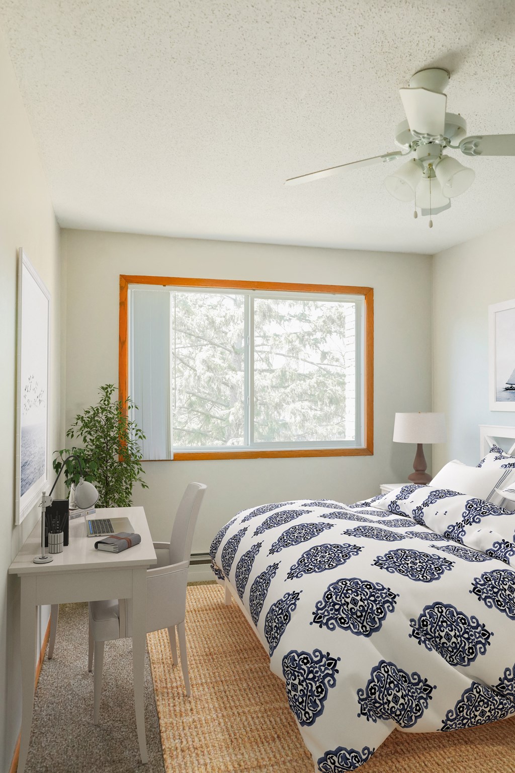 a bedroom with a bed with a blue and white bedspread and a white desk with a