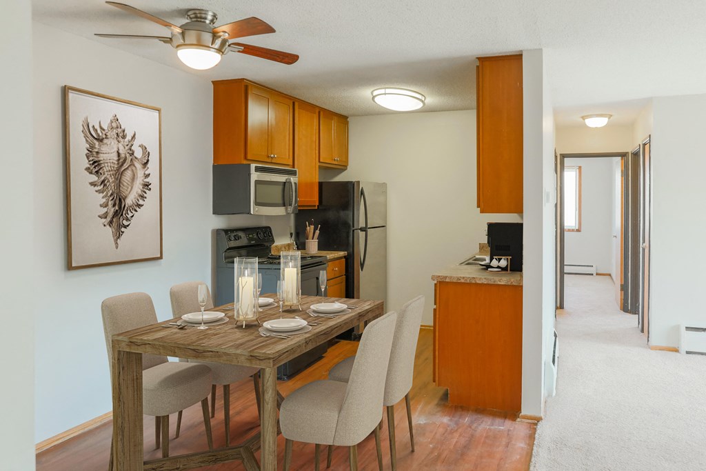 a dining area with a table and chairs and a kitchen in the background