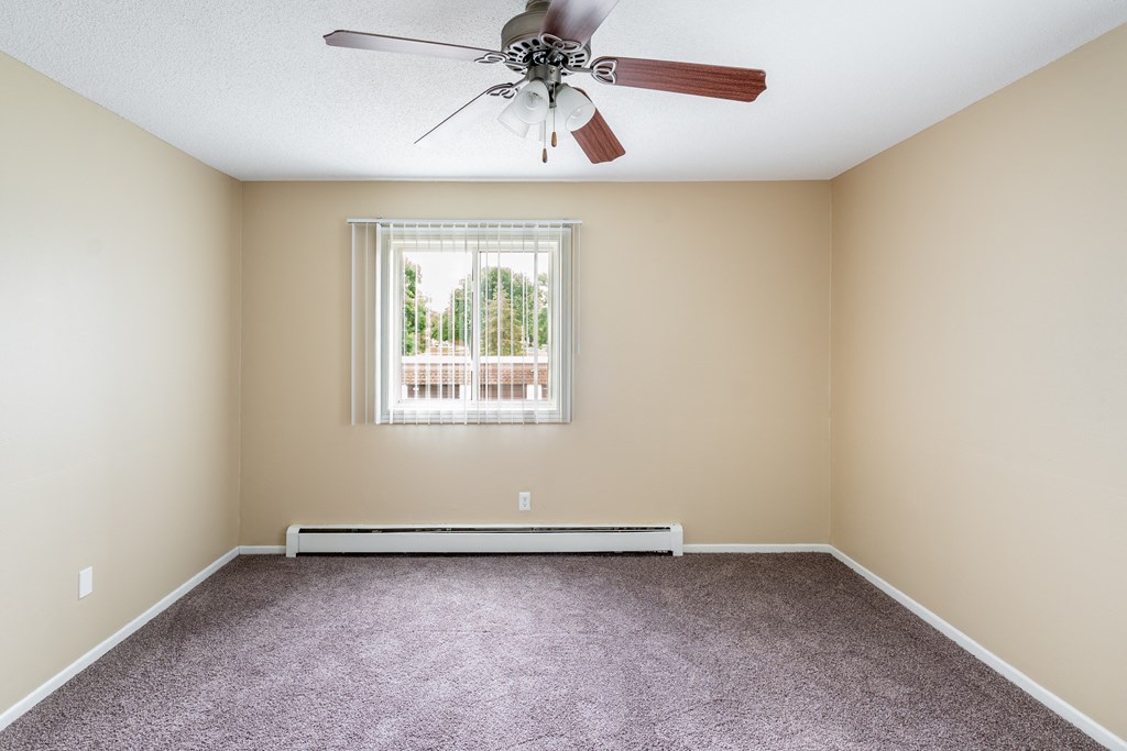 an empty room with a ceiling fan and a window