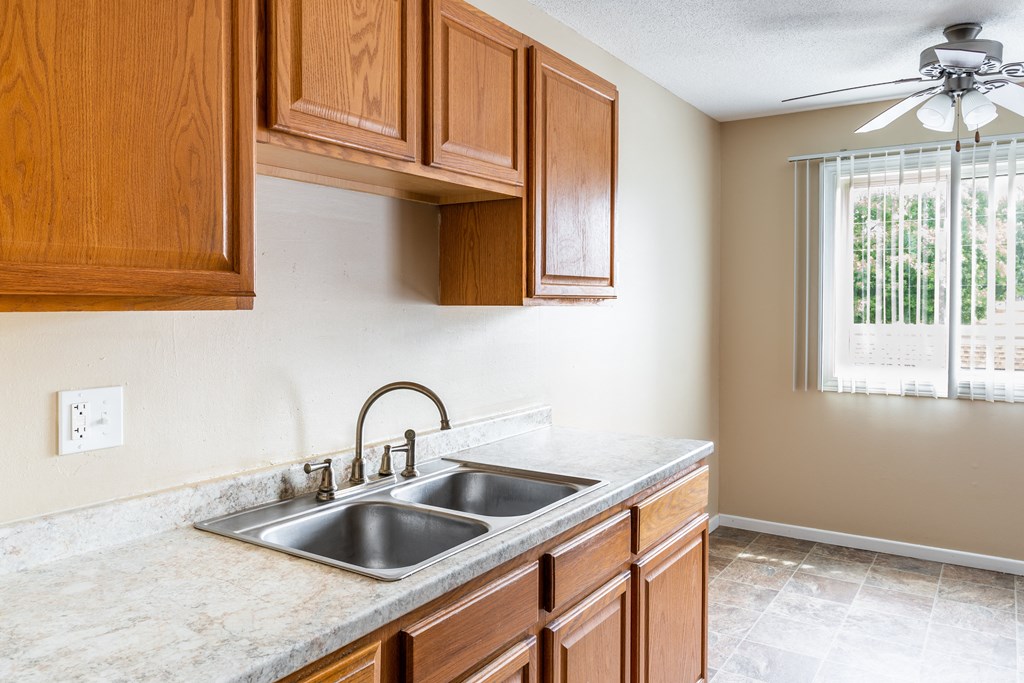a kitchen with wooden cabinets and a ceiling fan