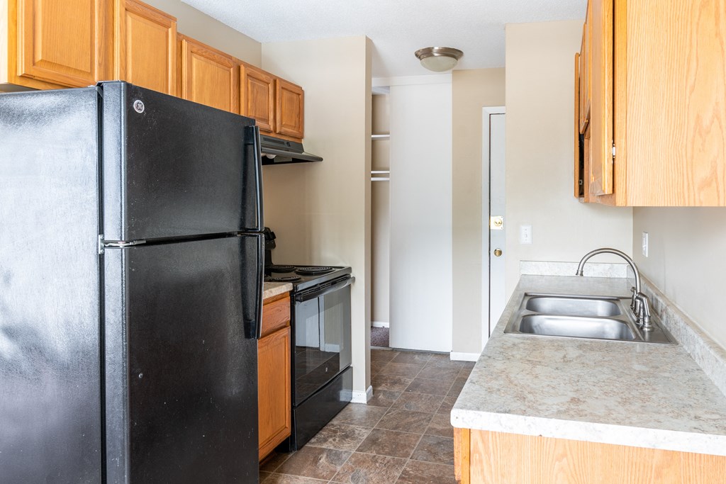 a kitchen with black appliances and wooden cabinets at Northtown Village Apartments, Spring Lake Park, 55432-2650
