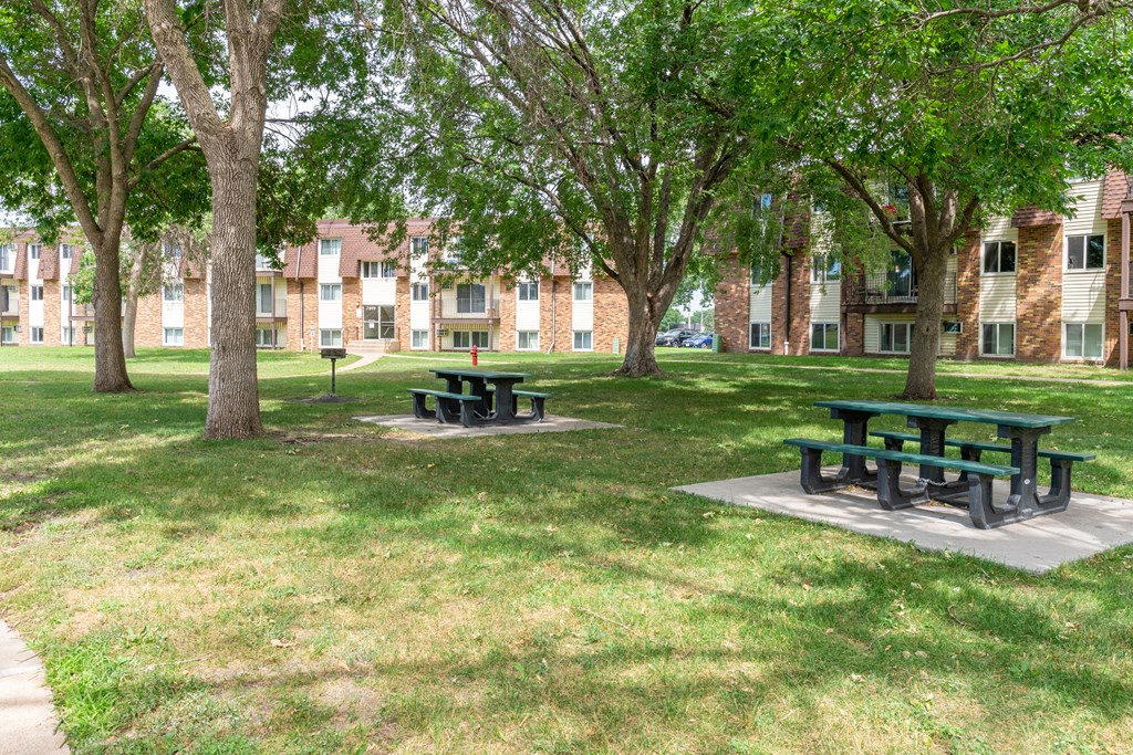 two picnic tables in a grassy area in front of a brick building at Northtown Village Apartments, Spring Lake Park, MN