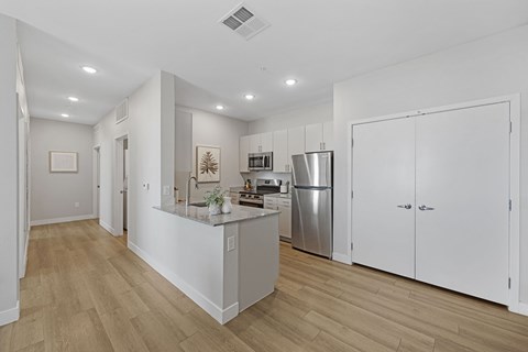 A kitchen with white cabinets and a wooden floor.