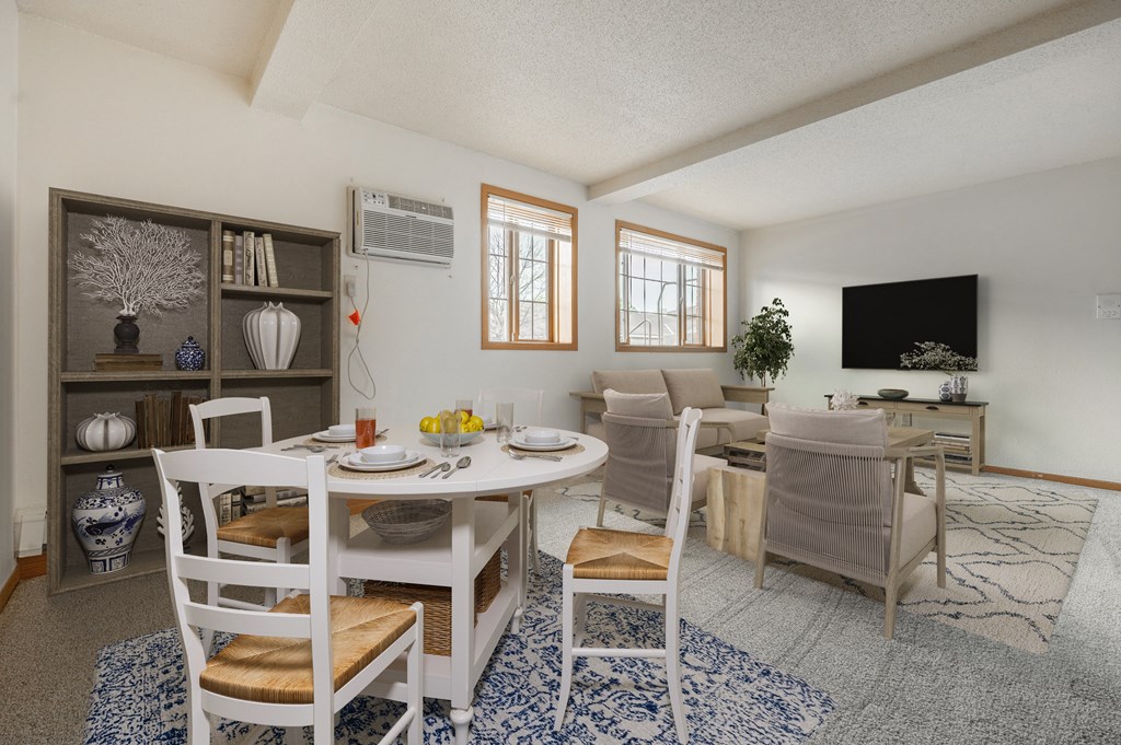 a living room with a white table and chairs and a flat screen tv on the wall