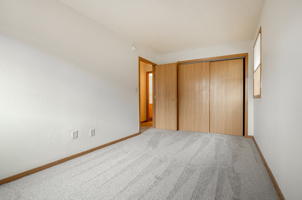 a bedroom with white walls and a door that leads to a hallway