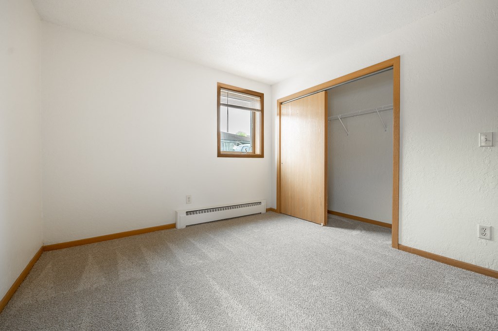 an empty bedroom with a closet and a window