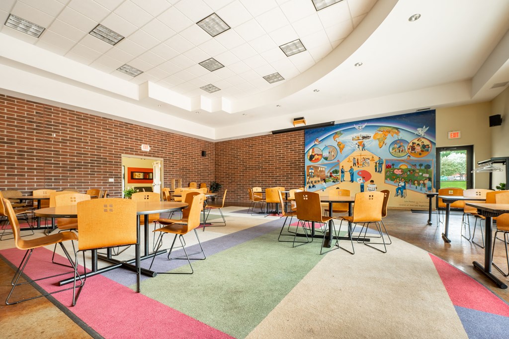 a large room with tables and chairs and a mural on the wall