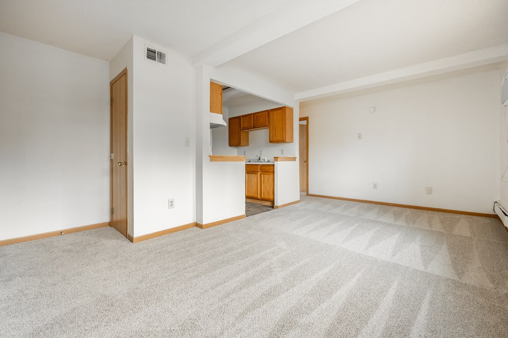an empty living room and kitchen with white walls and carpet at Ames Lake Neighborhood Apartments, Minnesota