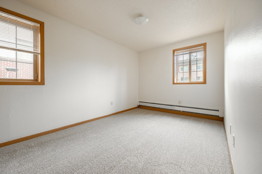 the living room of an empty house with white walls and two windows at Ames Lake Neighborhood Apartments, St. Paul, MN