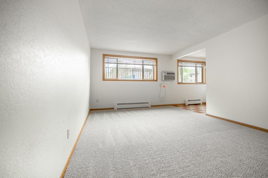 the living room and dining room of a house with white walls and a carpet at Ames Lake Neighborhood Apartments, St. Paul