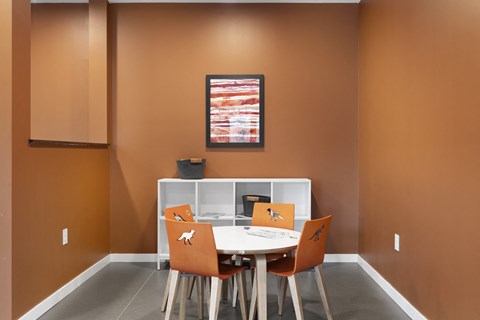 A dining room with a white table and orange chairs.