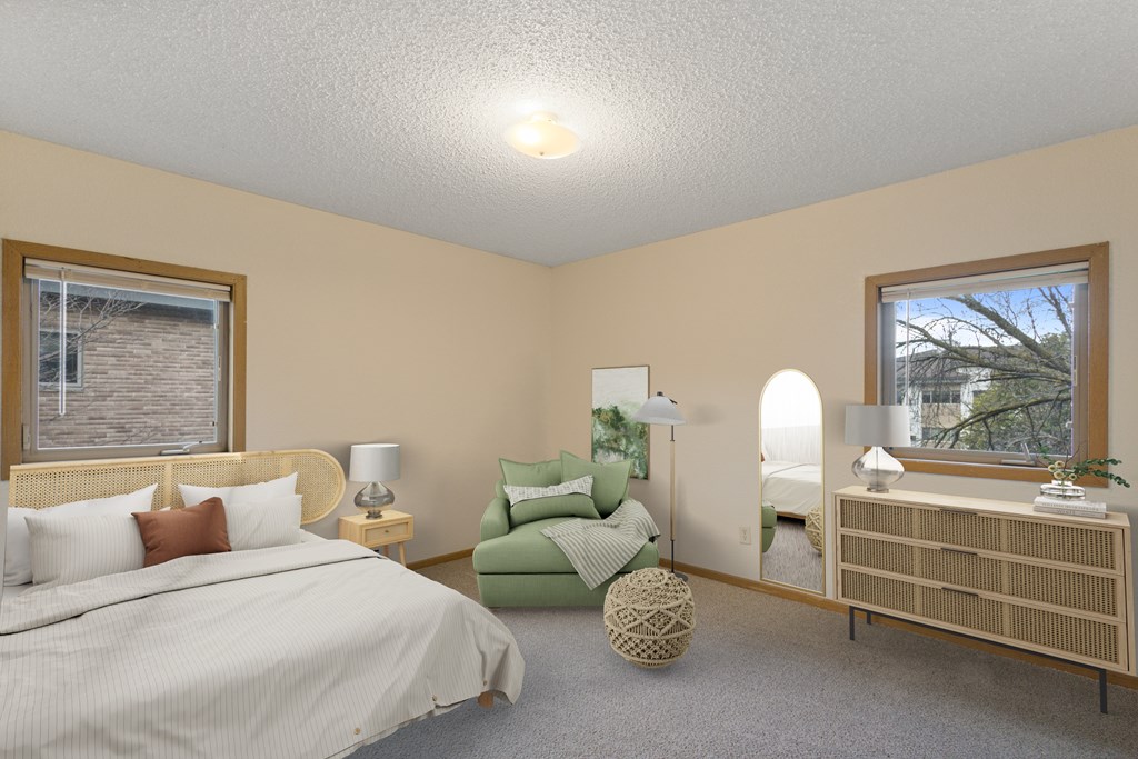 A bedroom with a bed, chair, and nightstand.