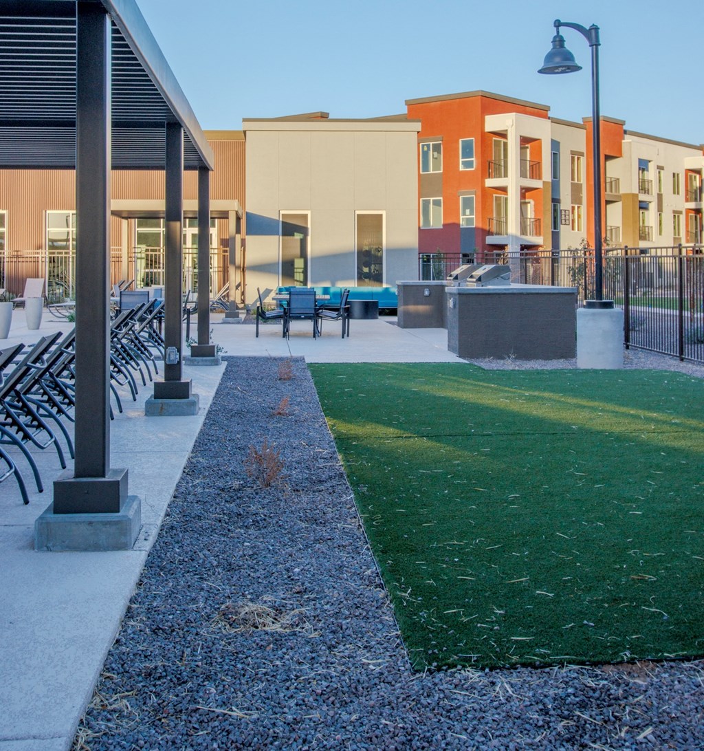 a grassy area with benches and a pool in front of a building