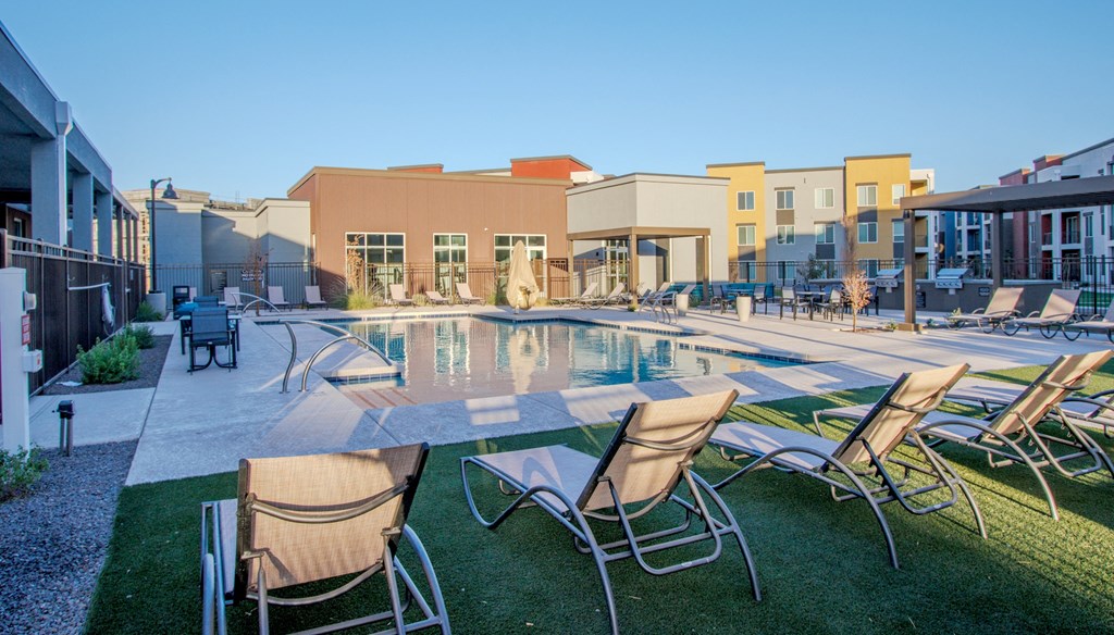 a swimming pool with chairs and a building in the background at Copa Flats, Maricopa, 85138
