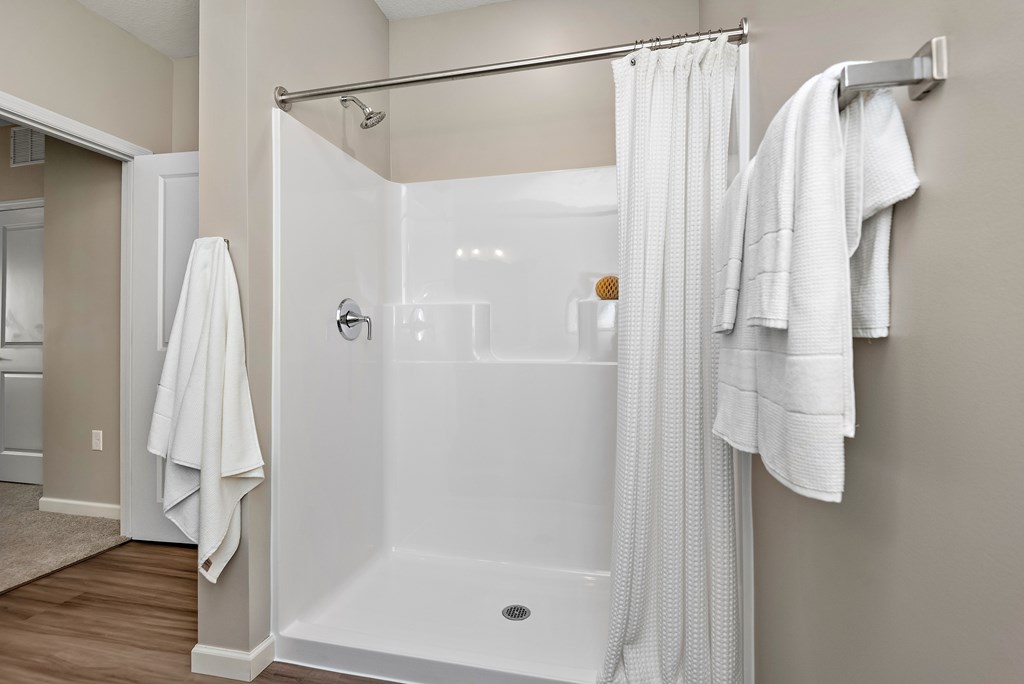 A white bathroom with a glass shower door and a white towel hanging on the towel rack.