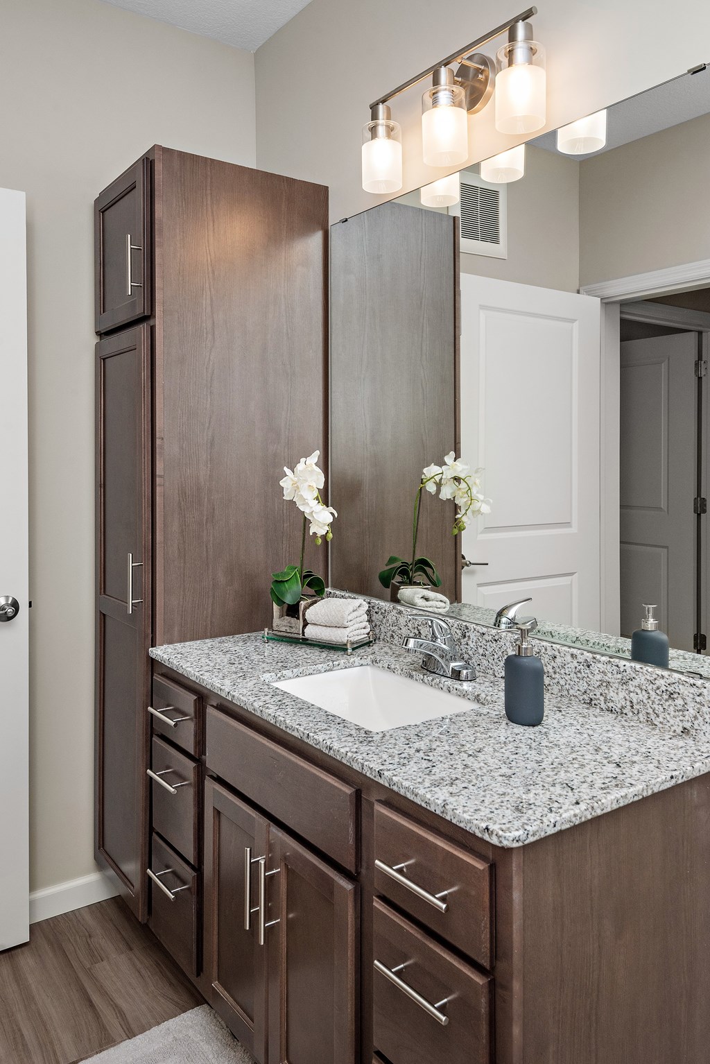 A bathroom with a sink, mirror, and wooden cabinets.