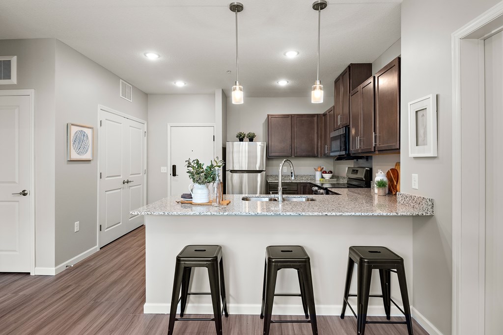 A kitchen with a granite countertop and bar stools.