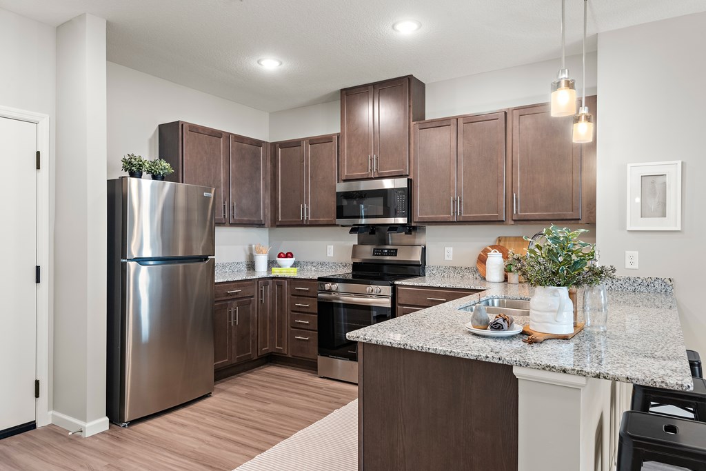 A kitchen with brown cabinets and a stainless steel refrigerator.