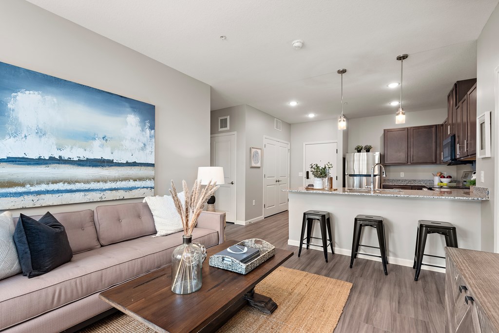 A living room with a couch, coffee table, and a painting of a beach scene on the wall.