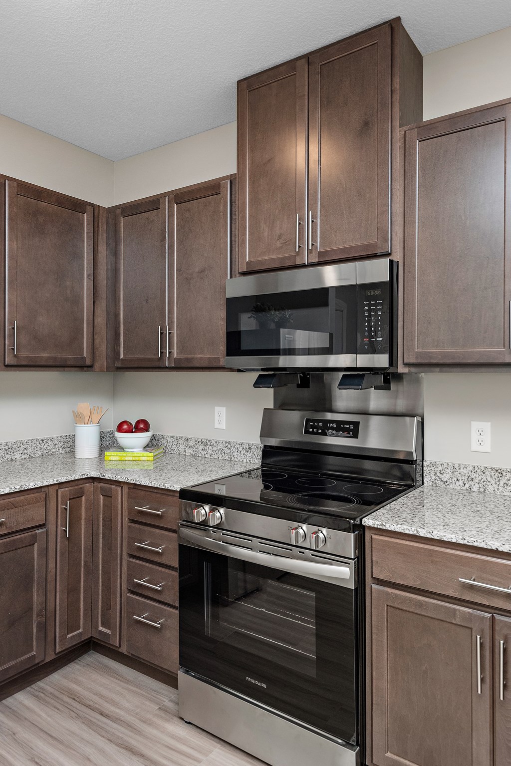 A kitchen with brown cabinets and a black microwave above a stove.