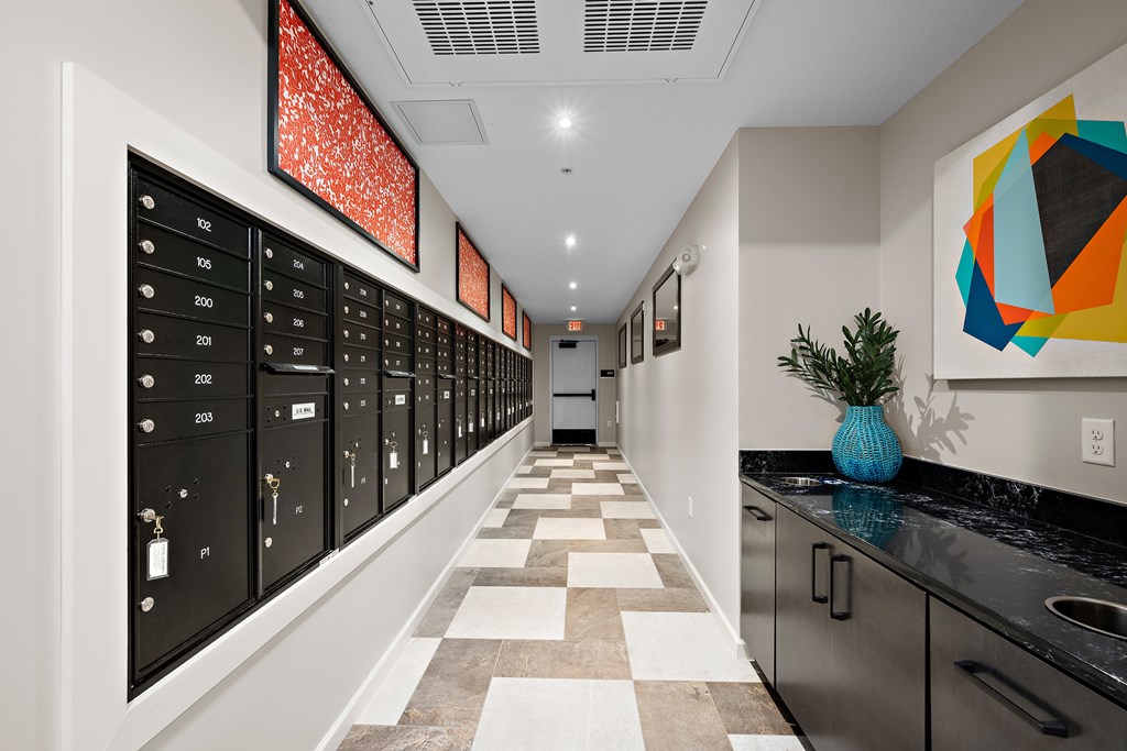 A hallway with a series of lockers on the left and a plant on the counter.