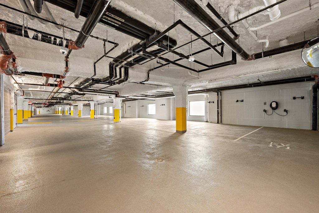 A large, empty warehouse with yellow bollards and exposed pipes.