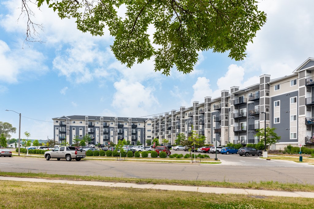 a rendering of a large apartment complex with cars parked in front of it