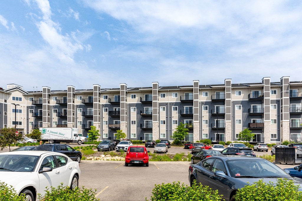 a photo of an apartment building with a parking lot in the foreground
