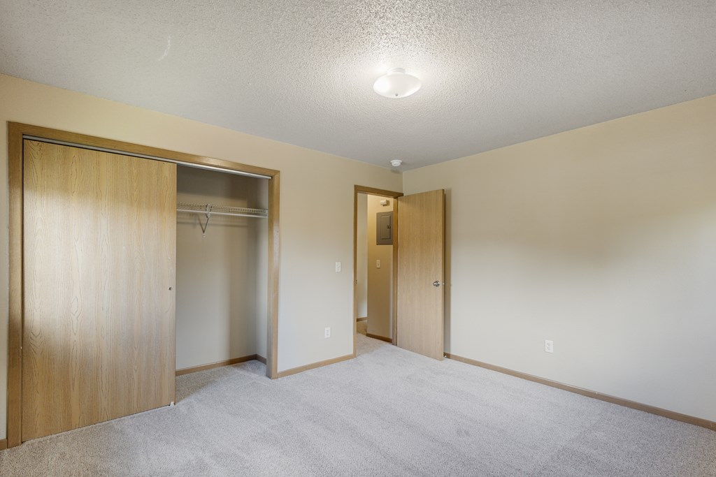 A room with a carpeted floor and two open doors at Ames Lake Neighborhood Apartments, St Paul 55106